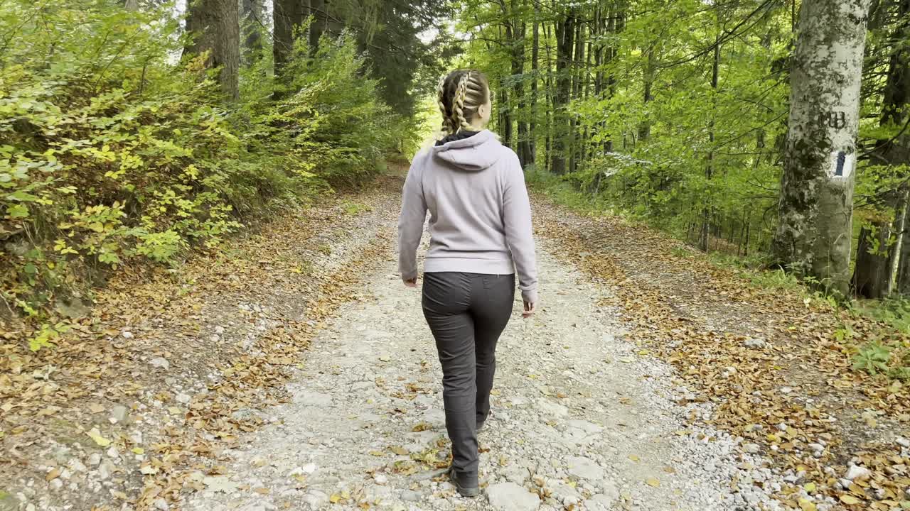 mujer caminando sola en el camino hacia el bosque en las montañas bucegi, rumania