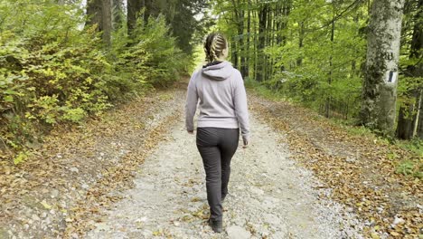 mujer caminando sola en el camino hacia el bosque en las montañas bucegi, rumania