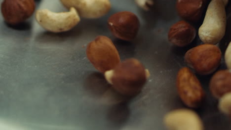 macro of nuts tossing on pan in slow motion. closeup cashews and hazel nuts