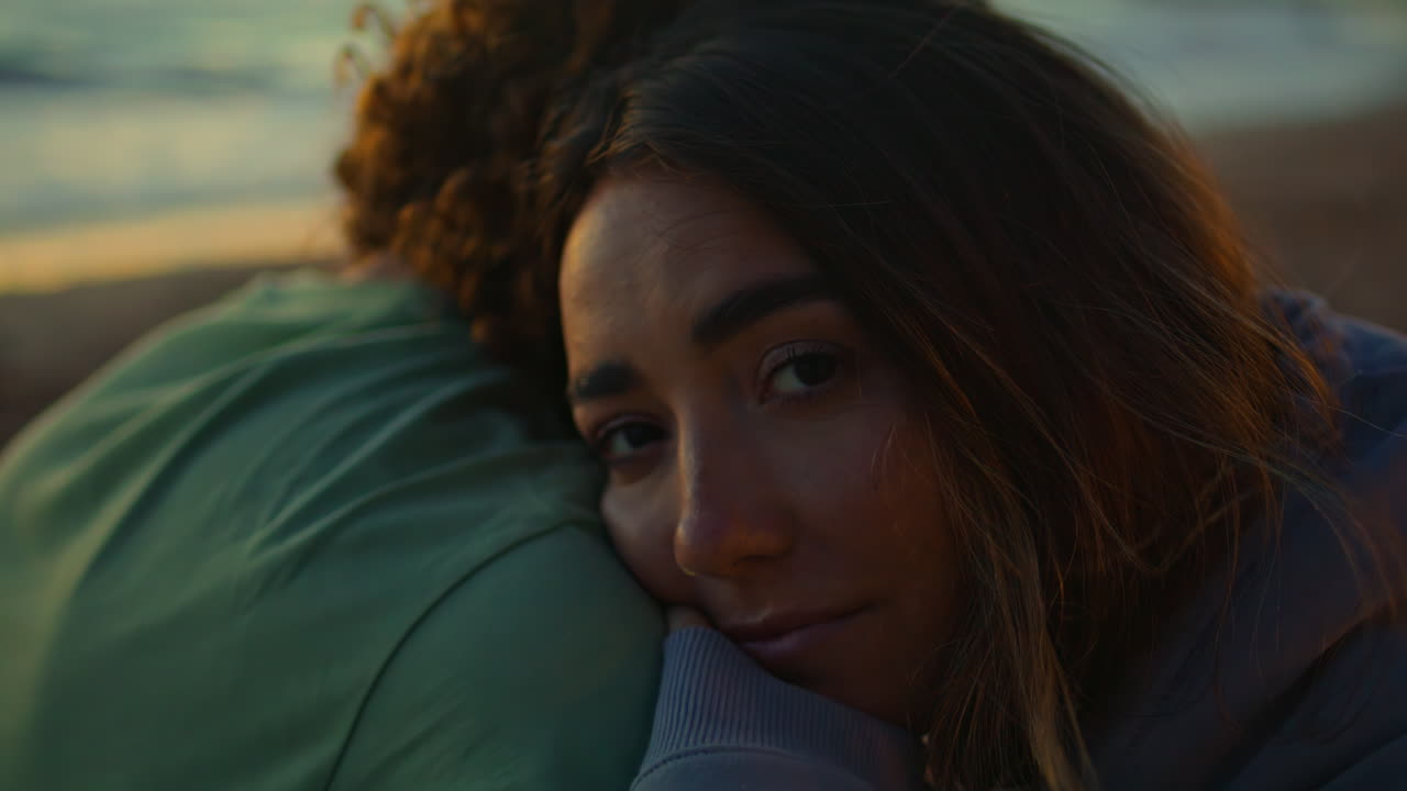 una chica triste abrazando a su novio en un primer plano de la costa nocturna.