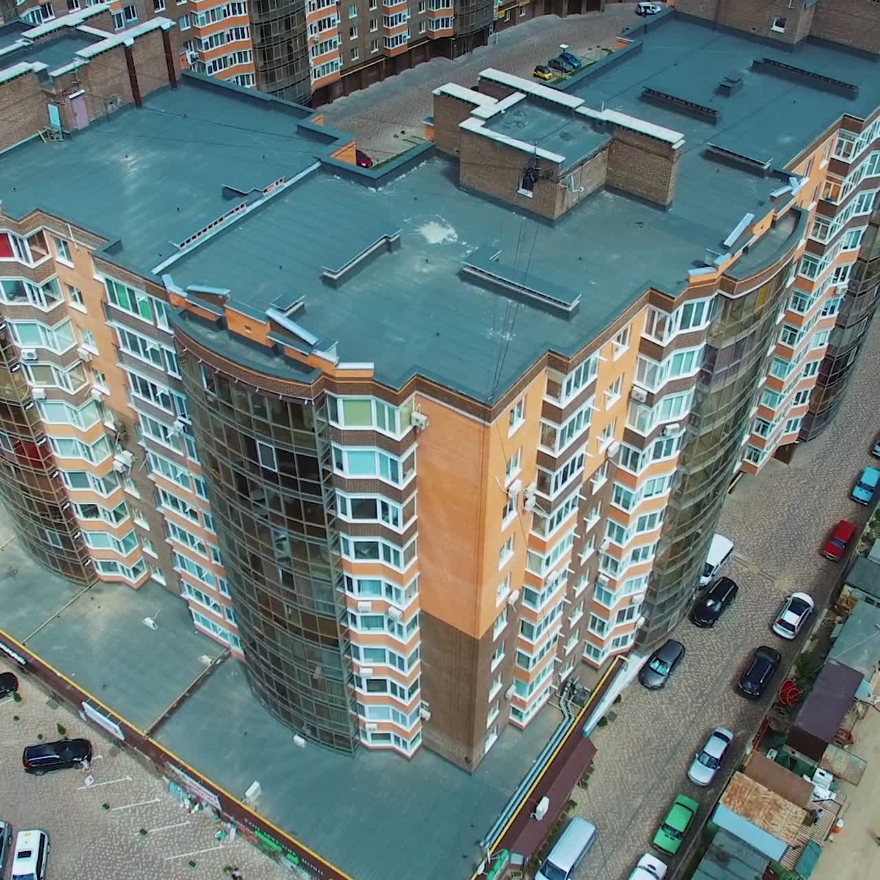 New apartment complex in the city. High-raised buildings near the road with moving cars. Modern infrastructure in downtown with car parking. Comfortable life in the city.