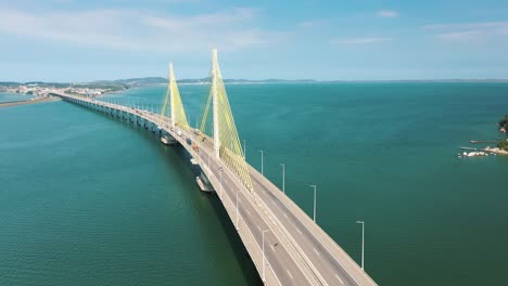 cinematic aerial shot bridge traffic above the turquoise color ocean, located in laguna, santa catarina, brazil