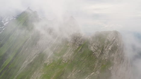 Rotierende-Drohnenaufnahme-Des-Altenalpturms,-Mit-Wolken,-Die-Den-Berghang-Bedecken