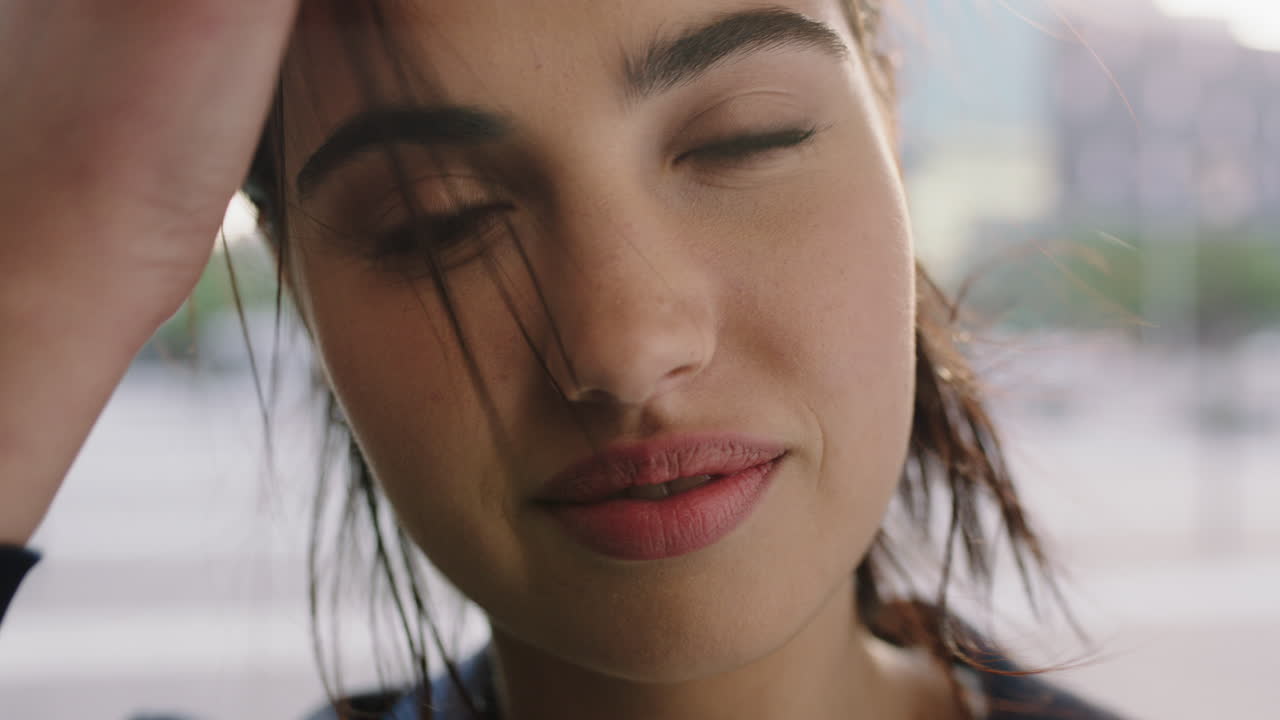 retrato en primer plano de una joven empresaria exitosa sonriendo a la cámara corriendo con la mano a través del cabello disfrutando del estilo de vida urbano de la ciudad ventosa