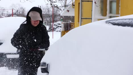 一个女人用刷子从车上清除雪 - 近距离