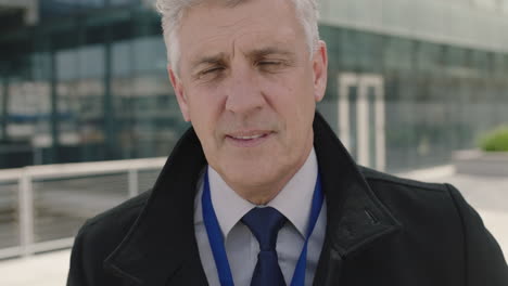 close up portrait of successful senior businessman checking messages using smartphone looking at camera smiling confident