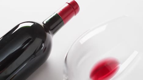 Red-wine-bottle,-empty-glass,-cork-and-corkscrew-lying-on-white-surface-with-copy-space