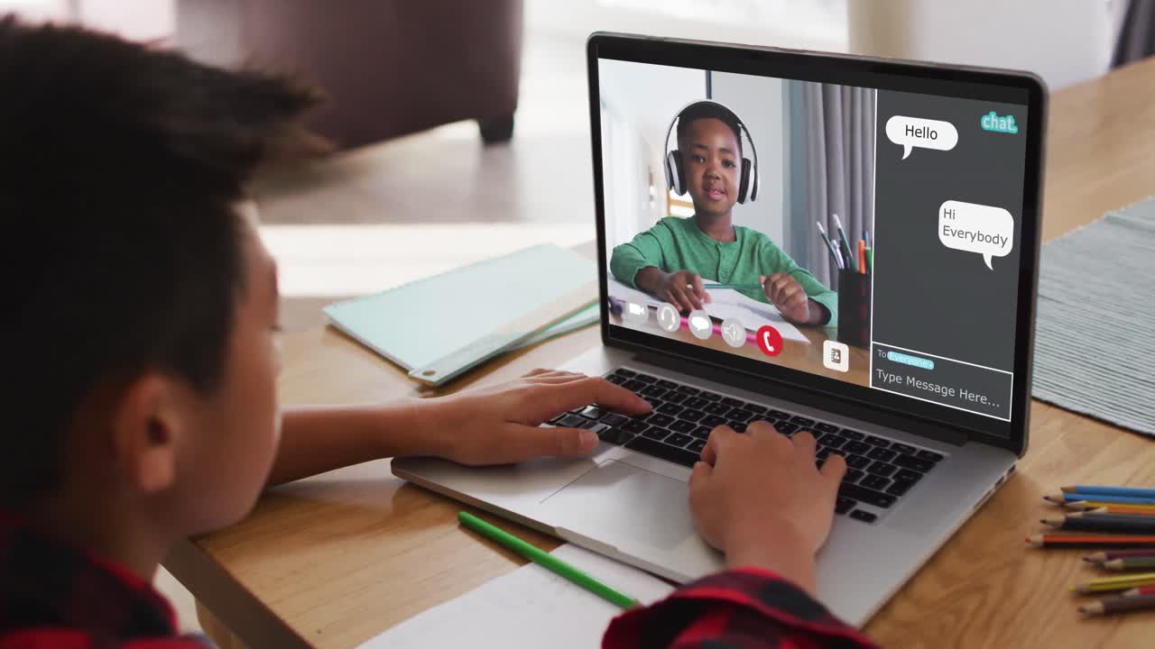 Schoolboy using laptop for online lesson at home, with boy talking and web chat on screen