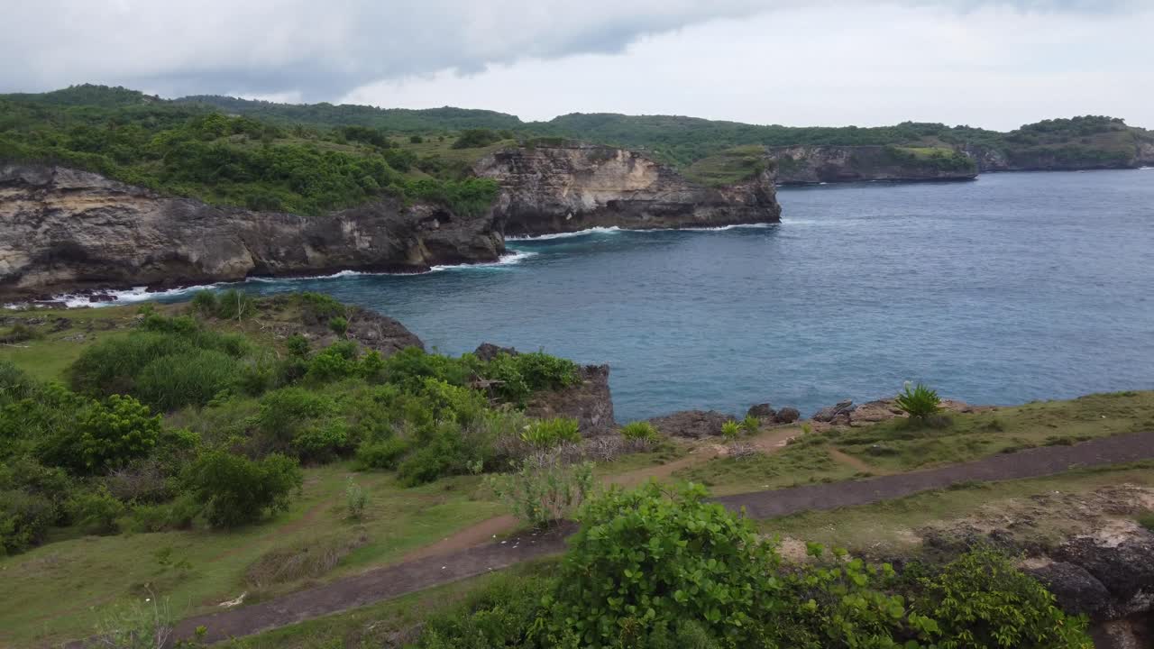 Ponte ad arco naturale di Broken Beach sull'isola di Nusa Penida con costa rocciosa lussureggiante e verde sullo sfondo
