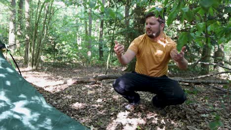 Young-man-looks-with-sadness-after-tent-string-snaps-in-woodland-area