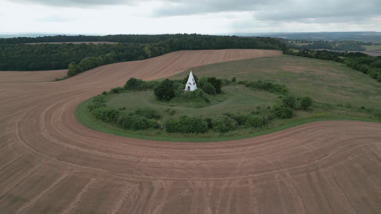 Drone dolly ascends above Farley Mount Monument, Winchester, UK, capturing the surrounding farmland and open countryside