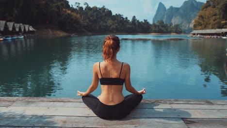 woman practicing yoga by a lake