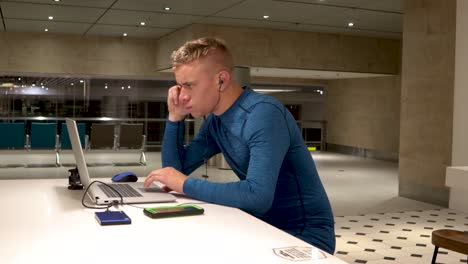 a young man working from his laptop at a table in changi international airport