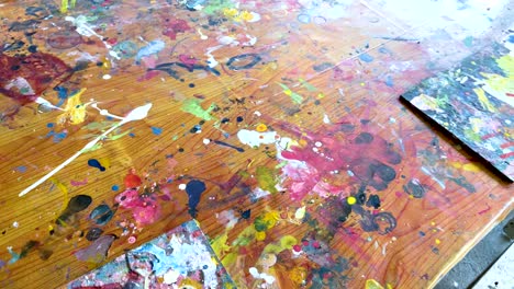 a vibrant display of paint splatters on a wooden surface, showcasing dynamic colors and artistic creativity in a lively setting