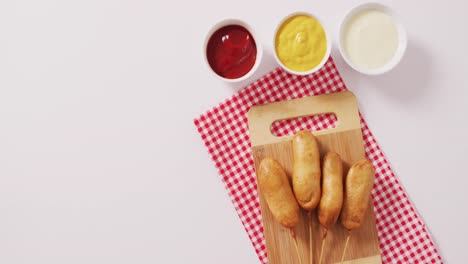 video of corn dogs with dips on a white surface