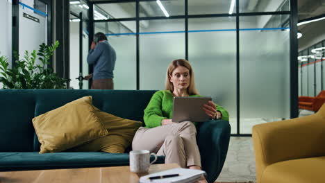 Dreamy-businesswoman-holding-pad-in-sofa-lounge.-Lady-boss-looking-tablet-screen