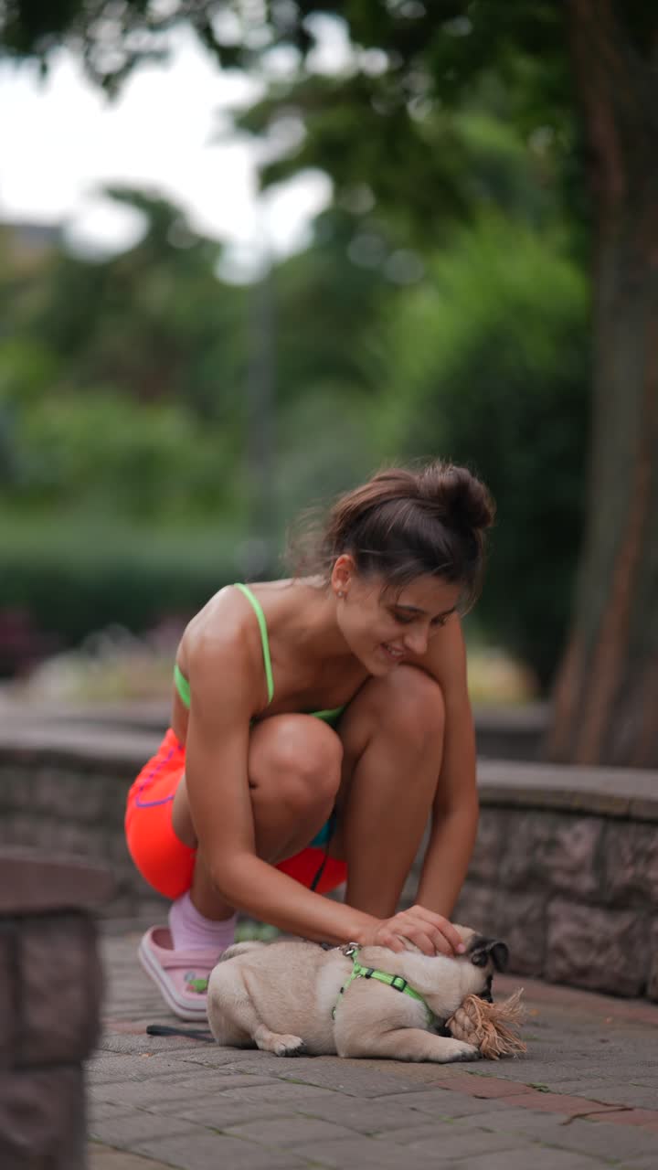 mujer jugando con su pug en un parque