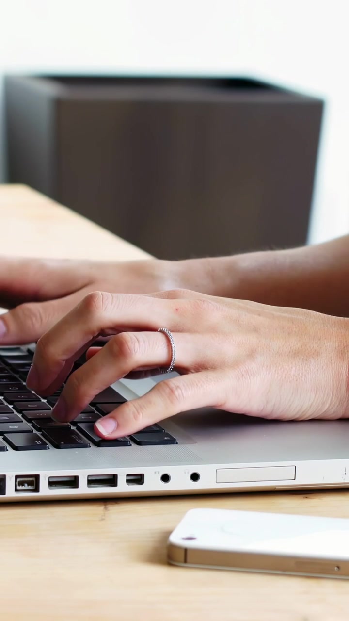 Video verticale: Mani che digitano vicino al telefono creando sovrapposizioni social con icone che svaniscono per il marketing