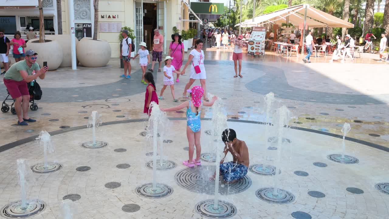 Kids Play in a Refreshing Street Fountain on a Sweltering Summer Day by La Explanada, Alicante, Spain.