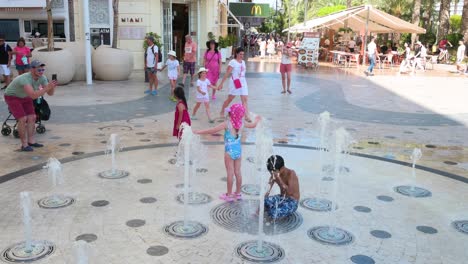 kids play in a refreshing street fountain on a sweltering summer day by la explanada, alicante, spain.