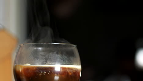 Whipped-cream-added-to-Irish-coffee-drink-in-slow-motion-on-black-bokeh-background