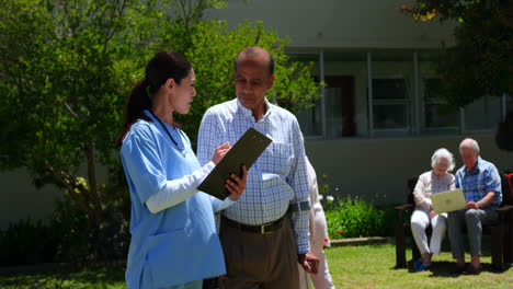 front view of active asian senior man and female doctor discussing over medical report in the garden