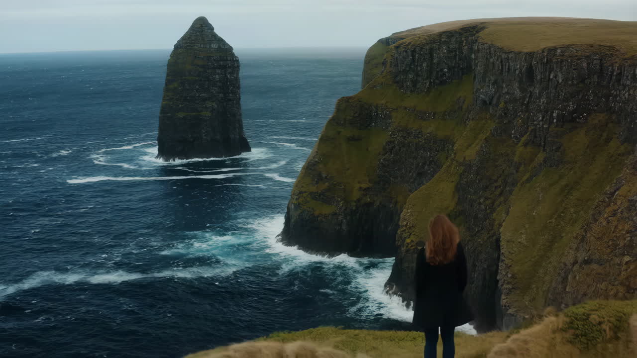 A person views a dramatic sea stack and rugged cliffs on a cloudy day