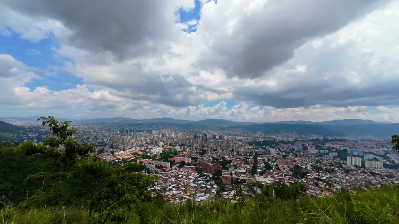 time-lapse vast metropolitan skyline nestled within a lush mountain valley, urban expansion and changing cloudscapes over a vibrant Latin American city. Caracas