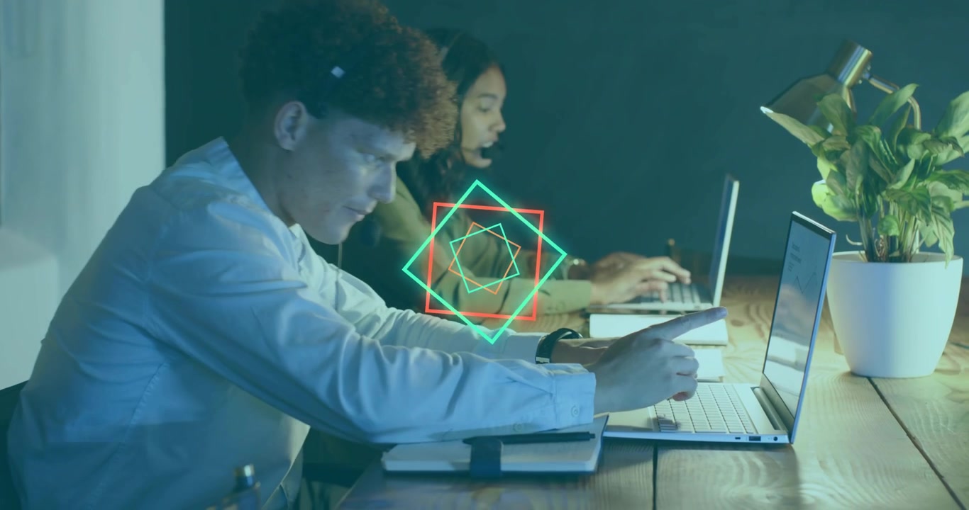 Uomo e donna che reagiscono al pulsare di grafiche al neon, digitando velocemente e prendendo appunti per una riunione tecnologica.