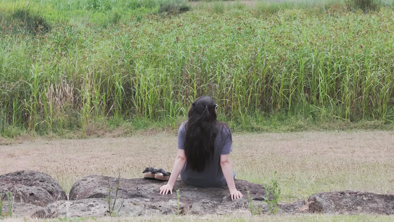 Momento sereno catturato mentre una donna si gode la tranquillità al Kilsyth South Park, Australia. La vegetazione naturale e le rocce rustiche creano un'atmosfera rilassante in questa inquadratura a mezzo busto.