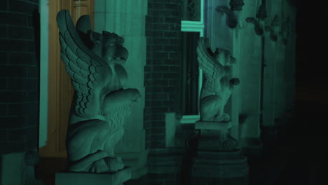 a gothic style stone gargoyle statue lit up by coloured lights