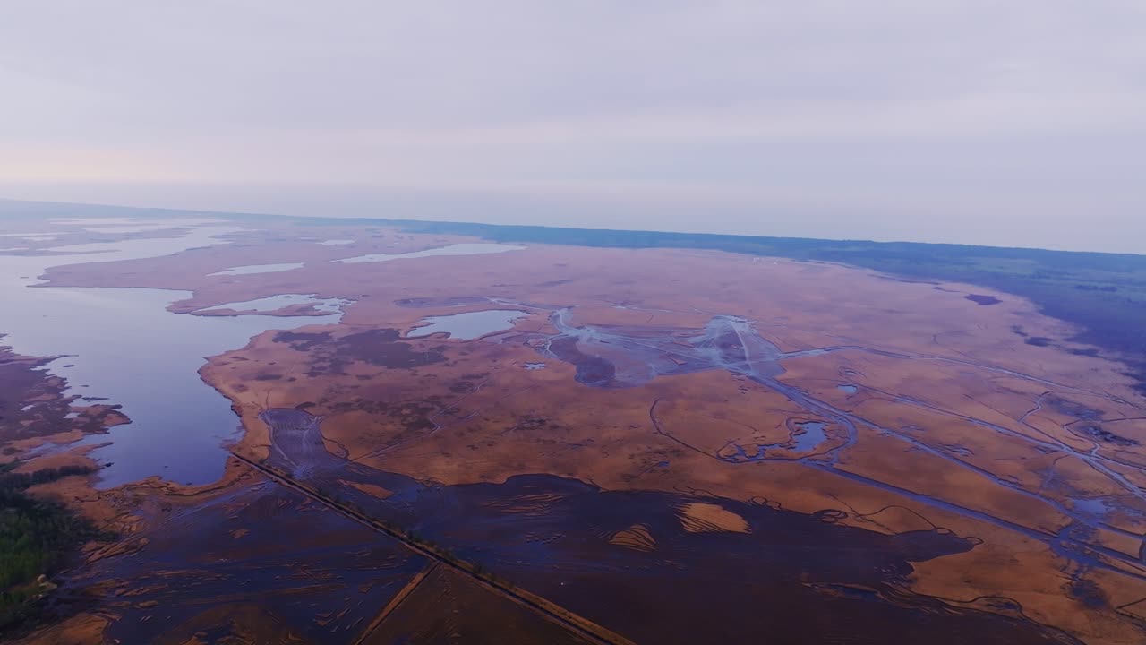 Expansive aerial scene where lake waters meet sea in tranquil atmosphere