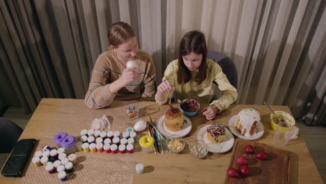 sisters decorating easter eggs and paschal bread