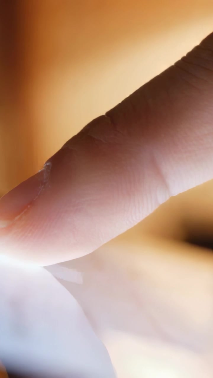 Vertical video: Approaching fingertip tapping, sliding on touchscreen in warm room to open app