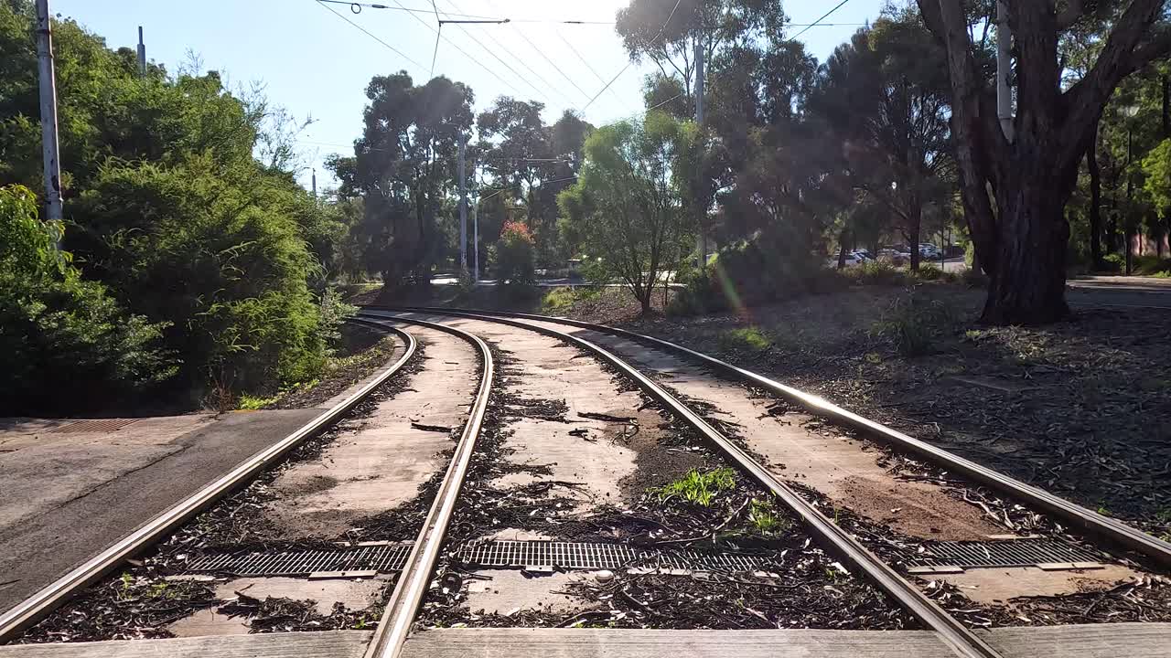 las vías del tren a través de un parque iluminado por el sol