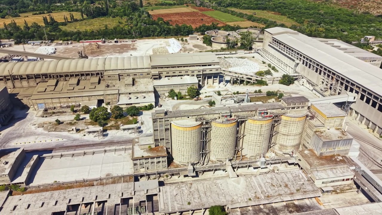 Altes Industriegelände mit hohen Bauwerken und weiten Flächen nahe grünen Feldern an einem sonnigen Tag tagsüber