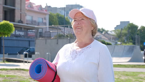 smiling elderly sports woman confidently walks in the morning park smiling elderly sports woman confidently walks in the morning park with the summer sun shining through the trees happy elderly woman