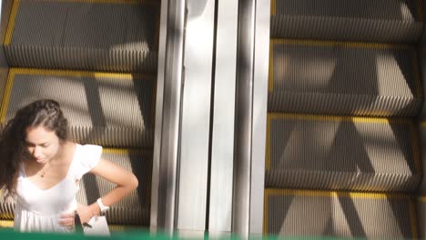 una mujer joven camina con bolsas de compras coloridas alrededor de un centro comercial una escalera mecánica