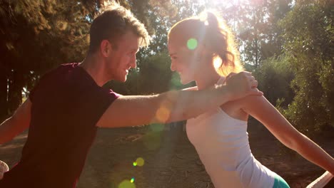 couple performing stretching exercise in olive farm