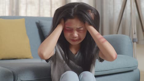 close up of young asian woman victim of violence with bruise on body having nervous breakdown and screaming while sitting on the floor at home