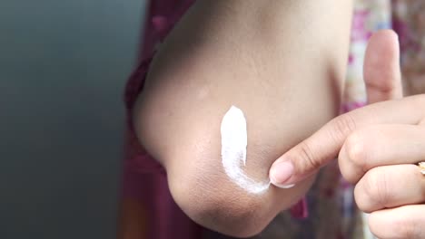 applying lotion to elbow