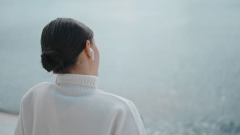 relaxed woman talking wireless headset sitting waterfront alone closeup vertical