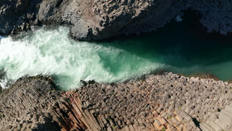 Top-down-view-Jokulsa-rough-water-river-flowing-through-Stuolagil-canyon-in-Iceland-highlands.-Overhead-view-basalt-rock-formation-in-Vatnajokull-national-park-and--glacier-river-streaming