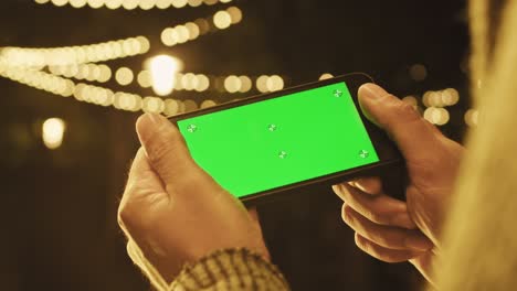 green screen smartphone. a man's hand holds a phone. scrolling on the green screen of the phone. smartphone footage.