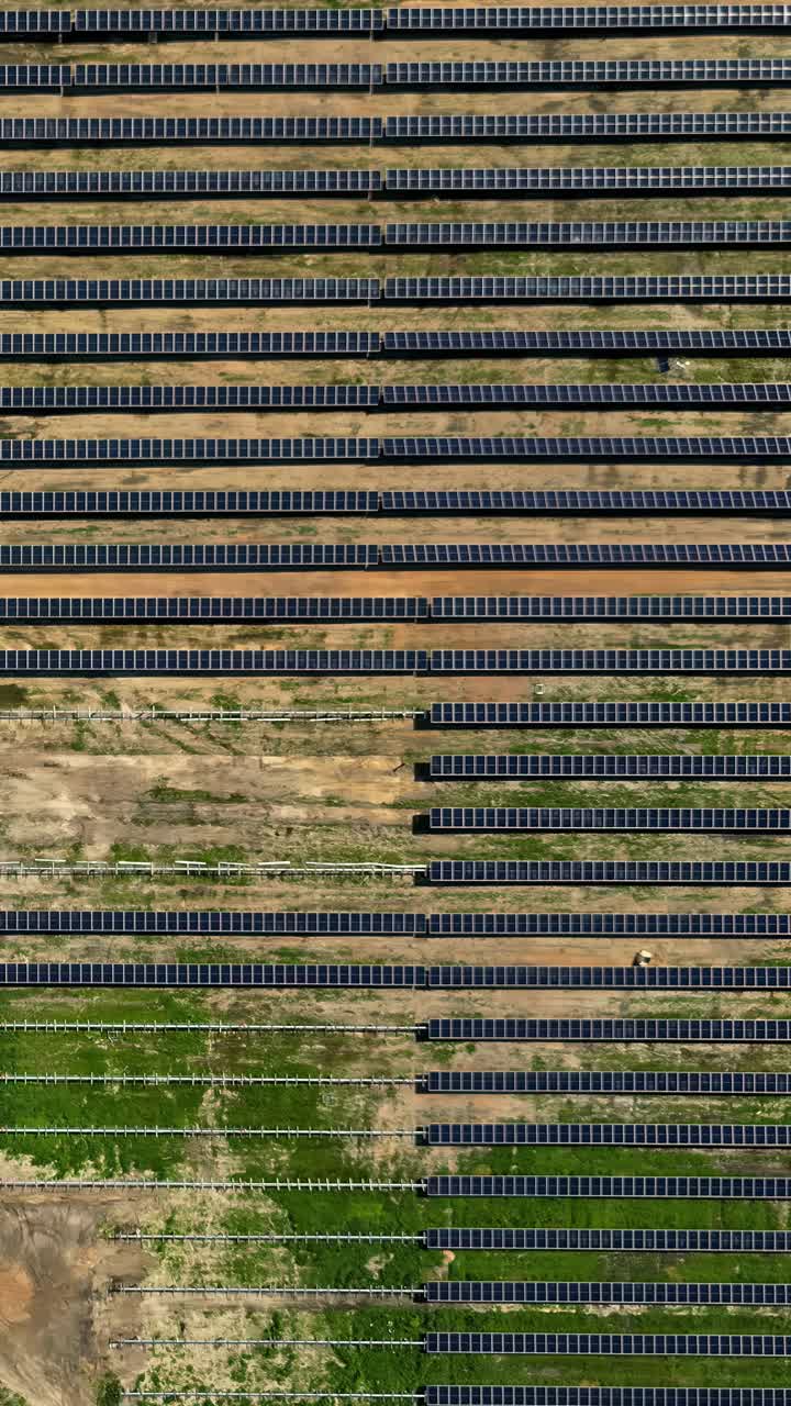 Solar energy farm during its construction in Latvia, showing the installation of new solar panels and their mounting frameworks - top-down aerial truck right