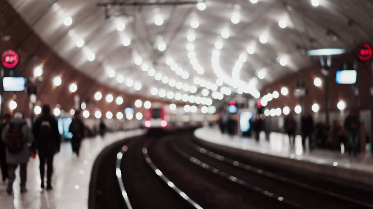 Blurry view of people and trains moving through the Monaco train station with bright lights in Monte Carlo, Monaco