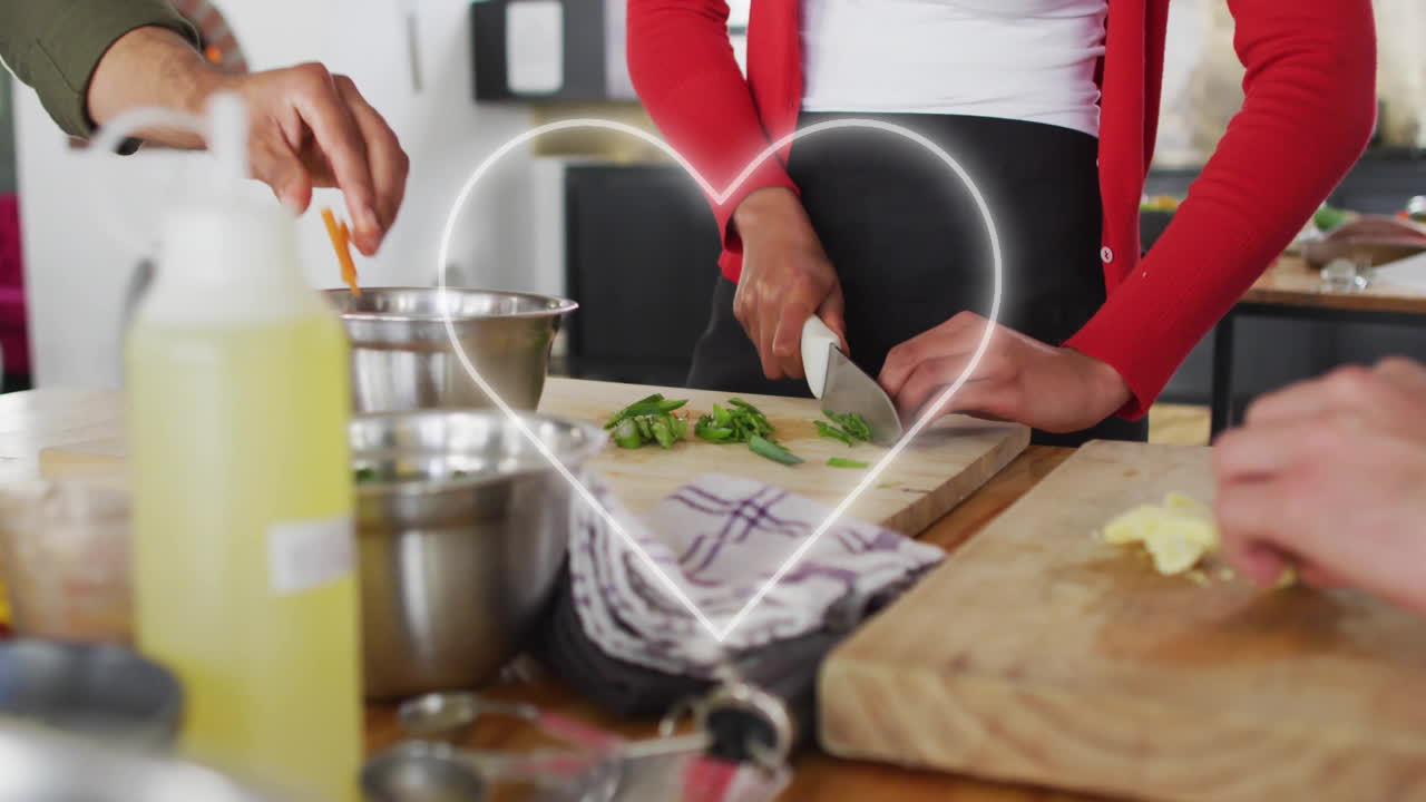 Person chopping vegetables in kitchen with glowing heart animation overlay