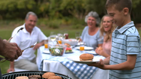 hombre sirviendo hamburguesa a un niño pequeño