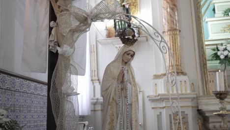 virgin mary statue with crown in an ornate church interior with floral decor