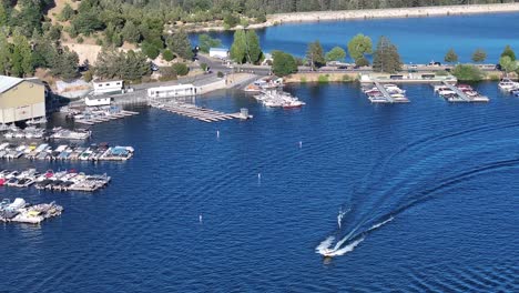 boats-moving-quickly-and-docked-up-on-lake-arrowhead-california-with-a-view-of-papoose-lake-on-a-bright-sunny-day-AERIAL-TRUCKING-PAN-telephoto-compression